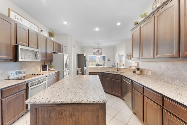 kitchen with a kitchen island, light tile patterned flooring, appliances with stainless steel finishes, and sink