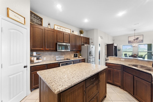 kitchen with sink, tasteful backsplash, light tile patterned floors, a kitchen island, and stainless steel appliances