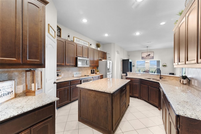 kitchen with light tile patterned flooring, sink, a center island, appliances with stainless steel finishes, and pendant lighting