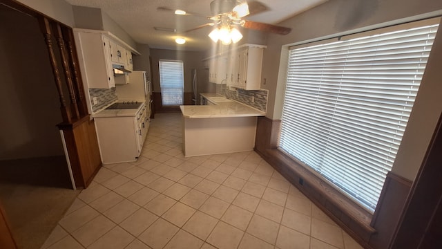 kitchen featuring light tile patterned floors, stainless steel fridge, ceiling fan, white cabinetry, and kitchen peninsula