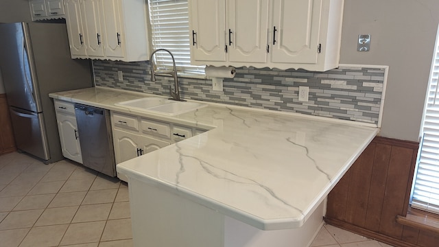 kitchen featuring sink, light tile patterned floors, white cabinetry, stainless steel appliances, and tasteful backsplash