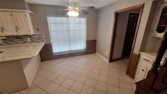 tiled dining space with ceiling fan, a textured ceiling, and wood walls