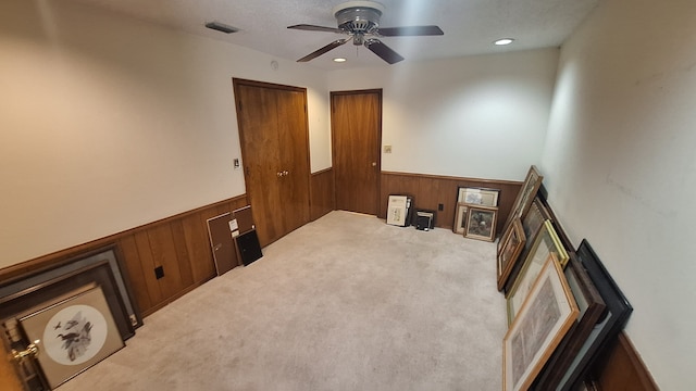 empty room with ceiling fan, wooden walls, and carpet