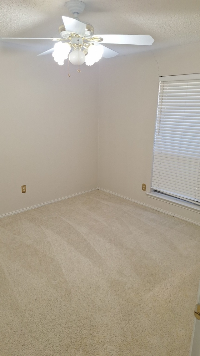 carpeted empty room with ceiling fan and a textured ceiling