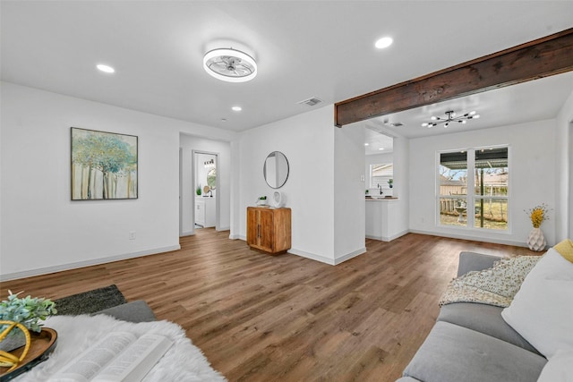 living room featuring beamed ceiling and light wood-type flooring