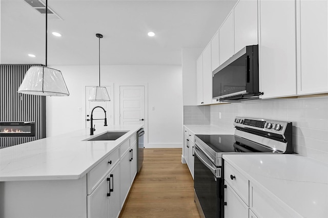 kitchen with sink, decorative light fixtures, a center island with sink, appliances with stainless steel finishes, and white cabinets