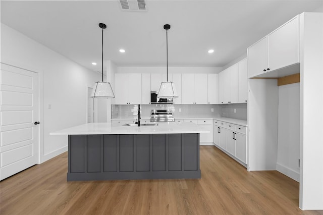 kitchen featuring decorative light fixtures, sink, stainless steel electric range, and white cabinets