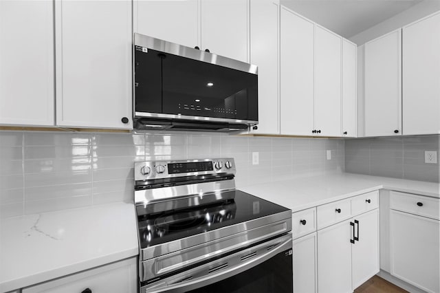 kitchen with electric stove, white cabinetry, and backsplash