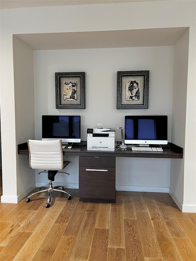 home office featuring hardwood / wood-style floors and built in desk