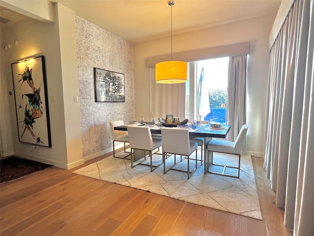 dining space featuring wood-type flooring and brick wall