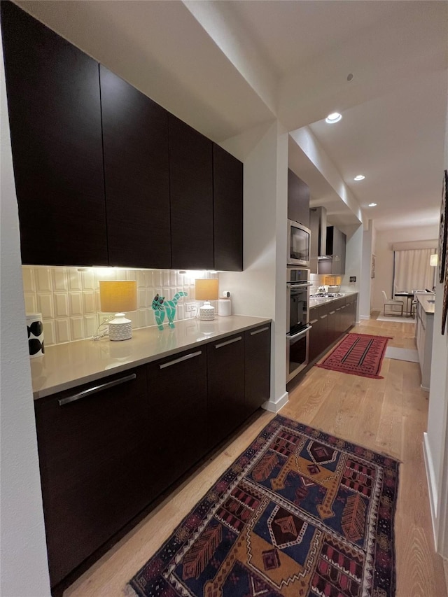 kitchen featuring tasteful backsplash, light hardwood / wood-style flooring, and appliances with stainless steel finishes