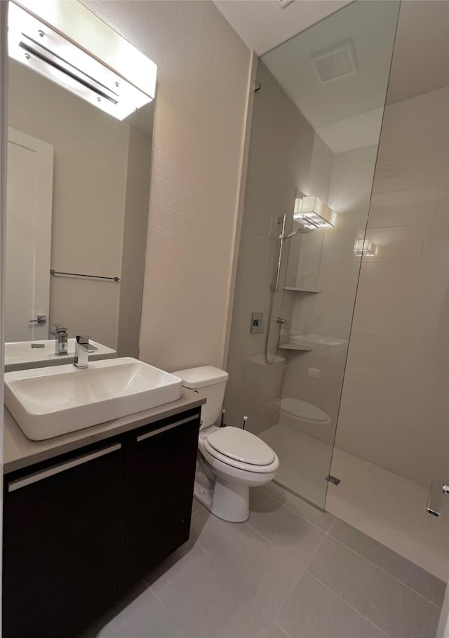 bathroom featuring walk in shower, vanity, toilet, and tile patterned flooring