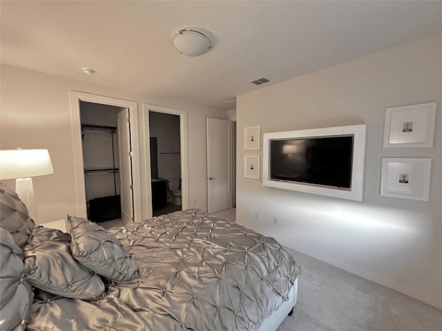 bedroom featuring a walk in closet, light carpet, and a closet