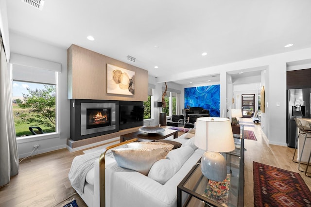 5399 Randwick Trl, Frisco, TX 75036 - living room featuring light wood-style floors, a glass covered fireplace, recessed lighting, and baseboards