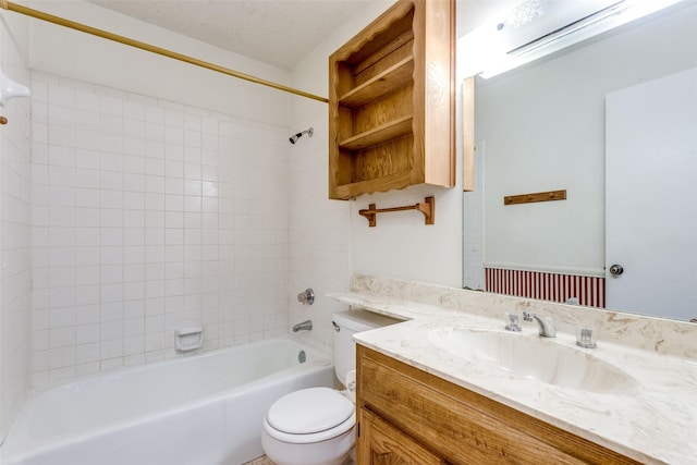 full bathroom with vanity, tiled shower / bath, toilet, and a textured ceiling