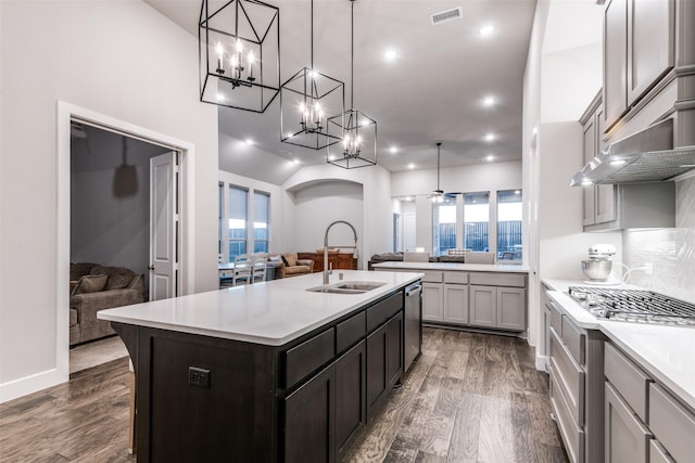 kitchen with a sink, visible vents, open floor plan, light countertops, and backsplash