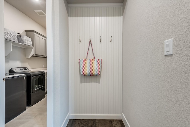 laundry room featuring cabinet space, light wood finished floors, baseboards, a textured wall, and independent washer and dryer