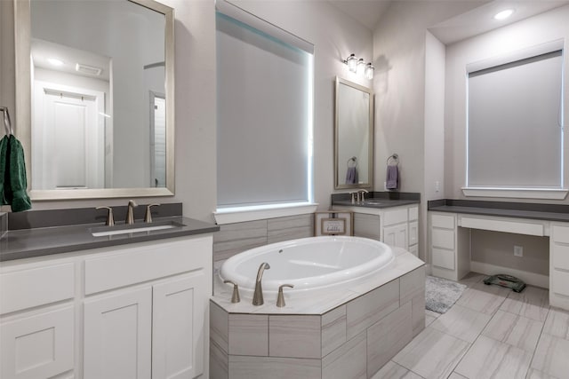 full bath featuring two vanities, a sink, and a bath