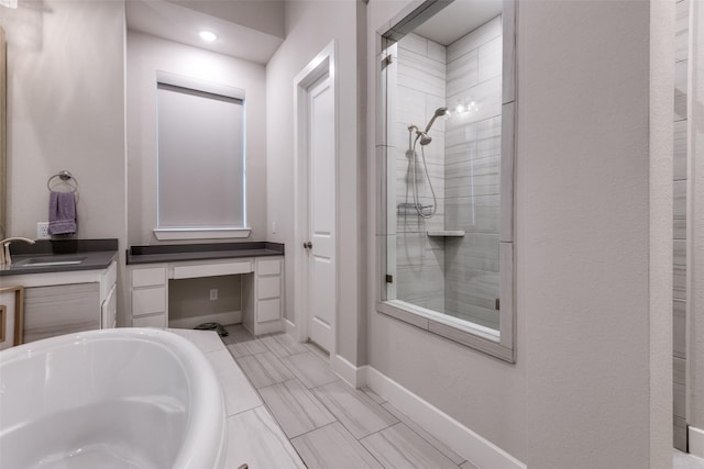 bathroom with a tub, a tile shower, vanity, and baseboards