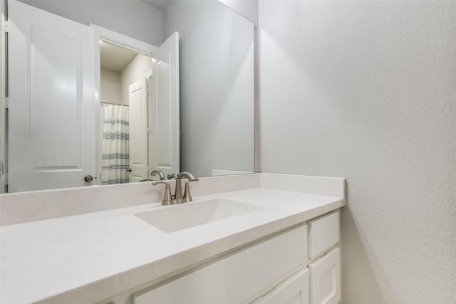 bathroom featuring a textured wall and vanity