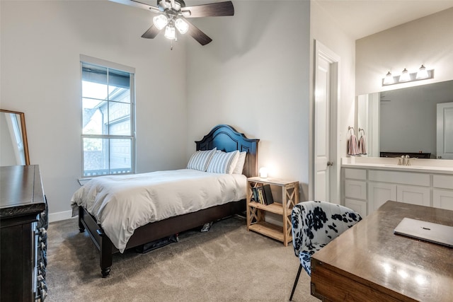 bedroom with connected bathroom, light colored carpet, a sink, a ceiling fan, and baseboards