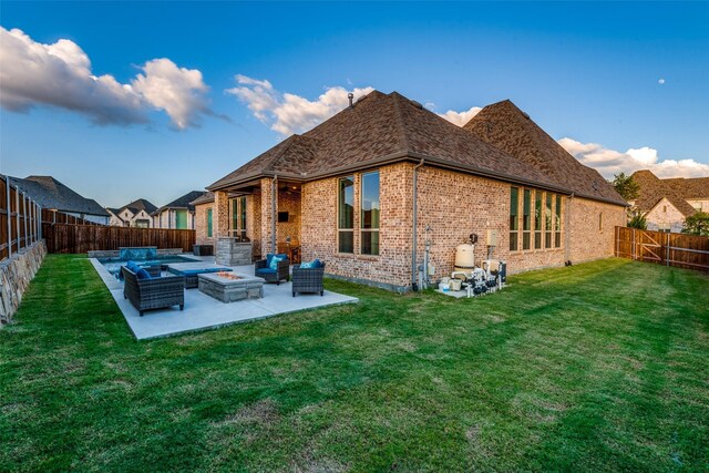 back of property featuring a fenced backyard, brick siding, a yard, a patio area, and an outdoor living space with a fire pit