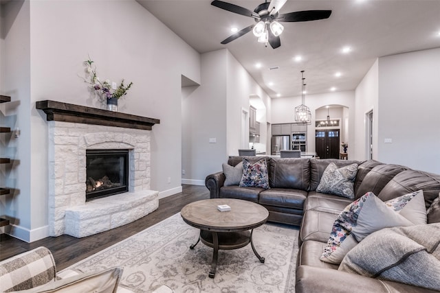 living room featuring arched walkways, a ceiling fan, wood finished floors, a stone fireplace, and recessed lighting