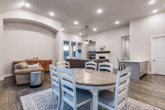 dining space featuring a stone fireplace, dark wood-type flooring, a ceiling fan, and recessed lighting