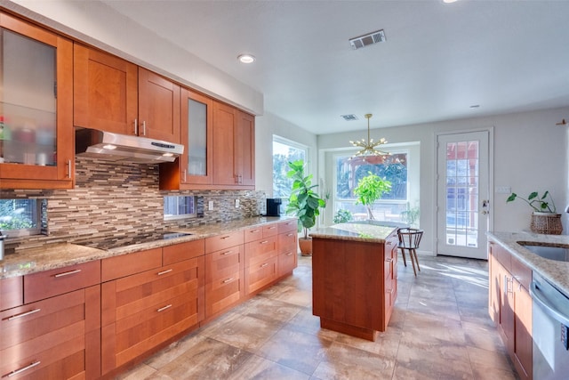 kitchen featuring light stone counters, decorative light fixtures, dishwasher, a kitchen island, and black electric stovetop