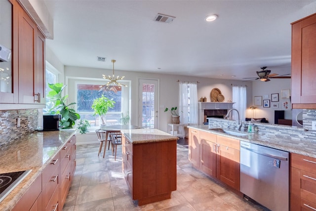 kitchen featuring sink, dishwasher, hanging light fixtures, backsplash, and light stone countertops