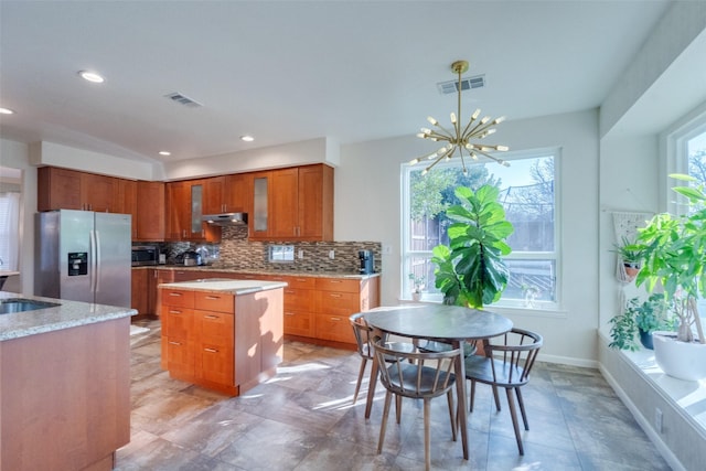 kitchen featuring sink, a kitchen island, a notable chandelier, stainless steel appliances, and backsplash