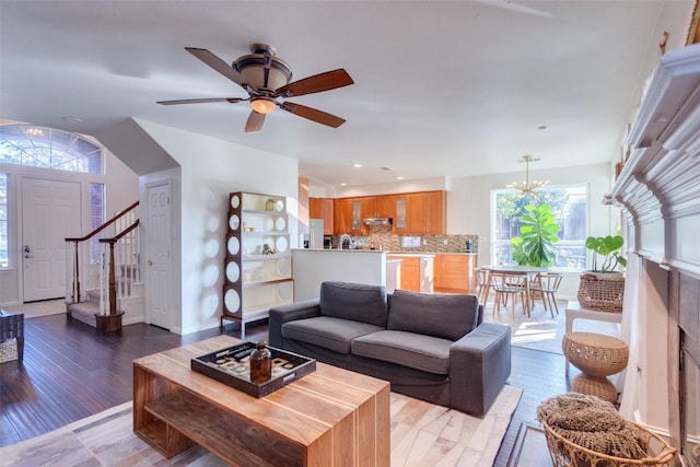 living room with ceiling fan with notable chandelier and hardwood / wood-style floors