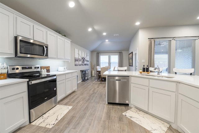 kitchen featuring sink, backsplash, stainless steel appliances, and white cabinets