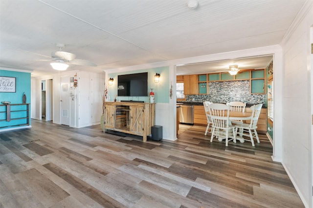 kitchen with wood-type flooring, stainless steel dishwasher, and crown molding