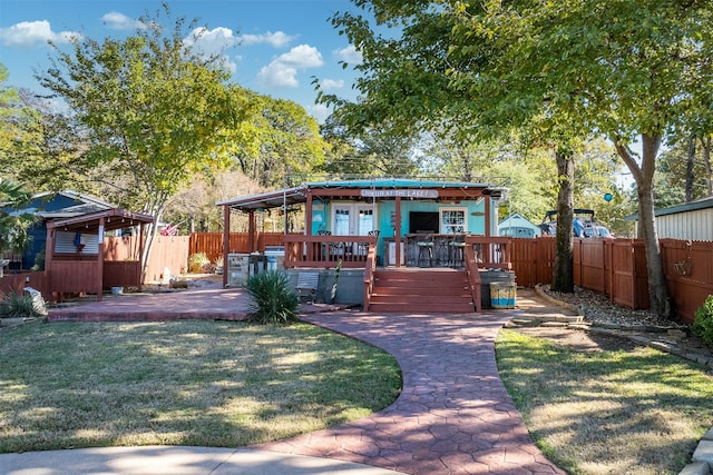 rear view of property featuring a wooden deck, a yard, and a patio