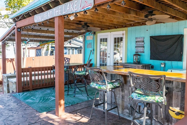 exterior space with french doors, ceiling fan, and a bar