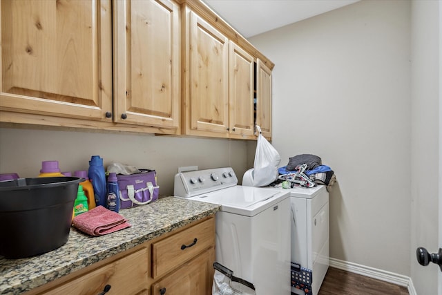 clothes washing area featuring cabinets, washing machine and dryer, and dark hardwood / wood-style flooring