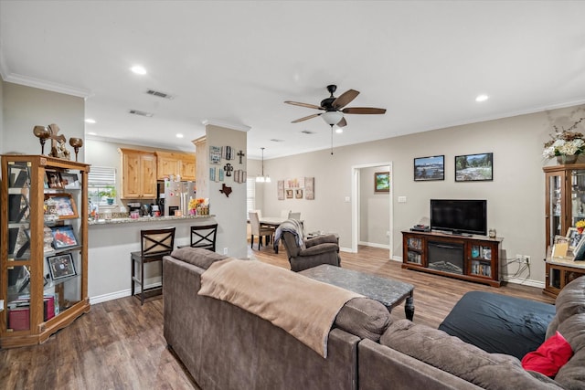 living room with dark wood-type flooring, ornamental molding, and ceiling fan