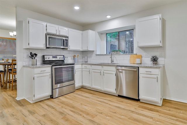 kitchen with white cabinetry, stainless steel appliances, sink, and light wood-type flooring