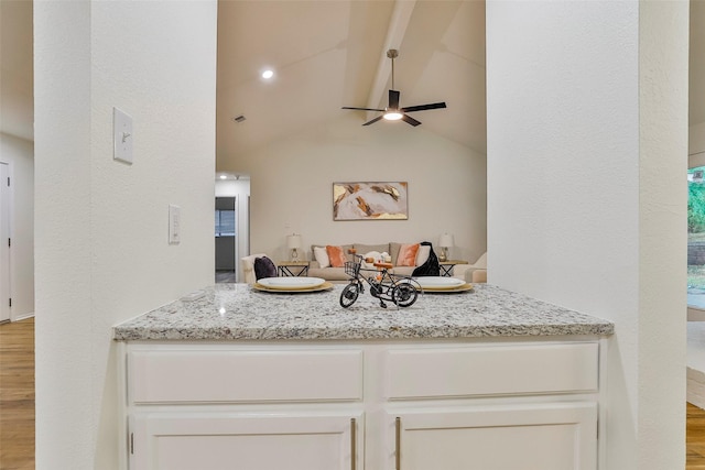 interior space featuring ceiling fan, light stone countertops, vaulted ceiling with beams, and light hardwood / wood-style floors