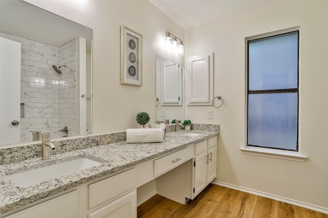 bathroom featuring vanity, wood-type flooring, and a tile shower