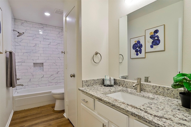 full bathroom with hardwood / wood-style flooring, vanity, toilet, and tiled shower / bath