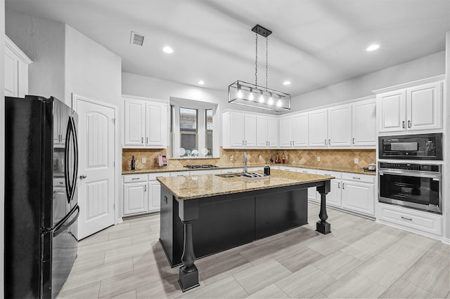 kitchen with sink, a kitchen island with sink, black appliances, white cabinets, and decorative light fixtures