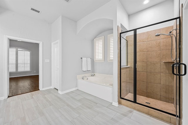 bathroom featuring a wealth of natural light and shower with separate bathtub