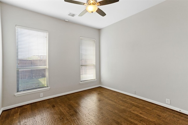 empty room with ceiling fan, plenty of natural light, and dark hardwood / wood-style flooring