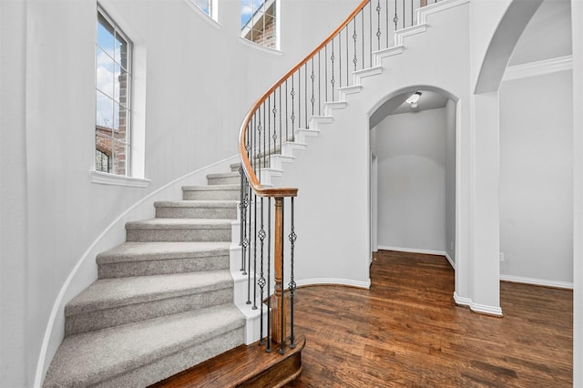 staircase with hardwood / wood-style floors and a high ceiling