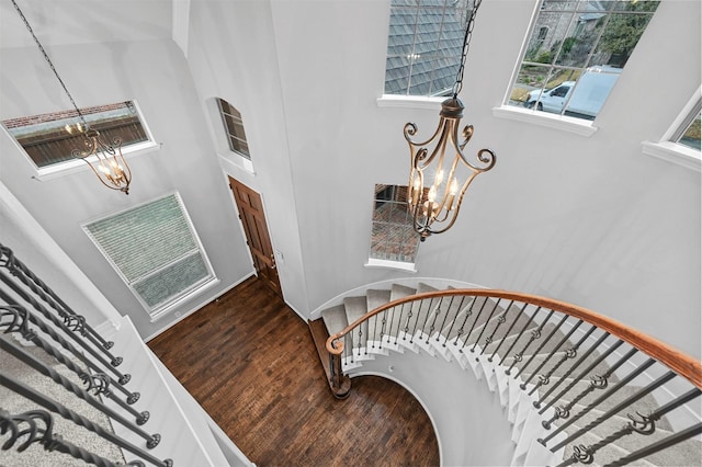 stairs with wood-type flooring and a notable chandelier