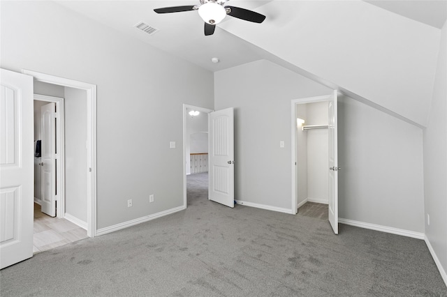 unfurnished bedroom with ceiling fan, light colored carpet, lofted ceiling, and connected bathroom