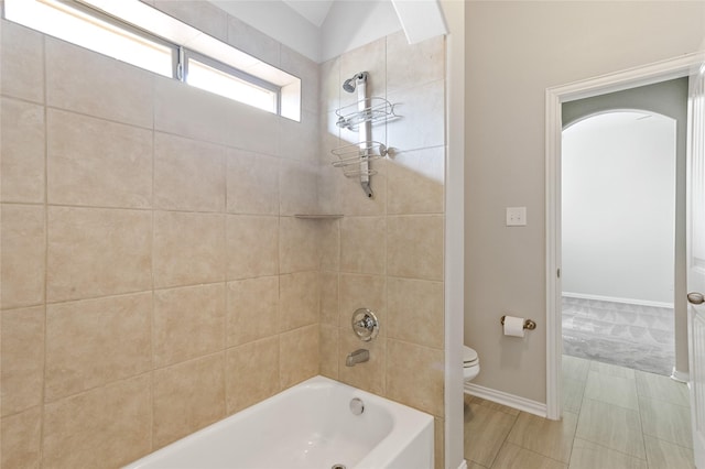 bathroom featuring tiled shower / bath combo and toilet