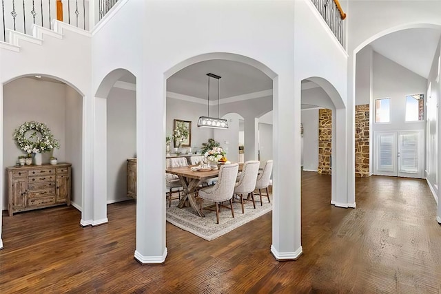 dining room with a towering ceiling, dark wood-type flooring, and ornamental molding